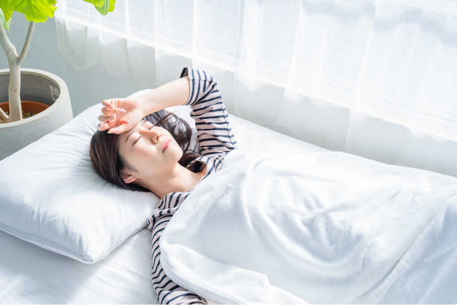 イメージ画像：ベッドで症状を覚えている女性